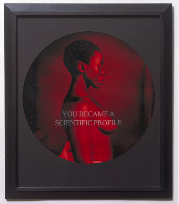 Photo of a framed image of a woman in black and red in profile pose, nude, cropped to a circle with the text You Became a Scientific Profile overlaied on top in light serif text